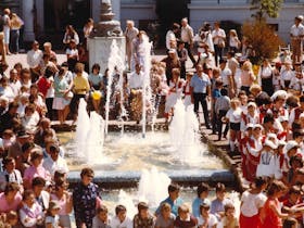 large crown gathered near a water fountain watching a performance