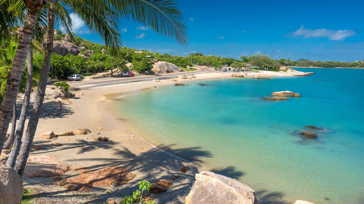Palm fringed Grays Bay in Bowen with sand and blue water