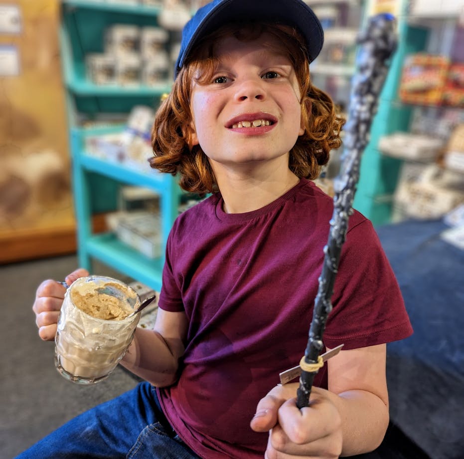 Photo of boy with a wand he made in a Quizzic Alley class and a QBrew in the other hand