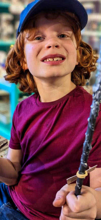 Photo of boy with a wand he made in a Quizzic Alley class and a QBrew in the other hand