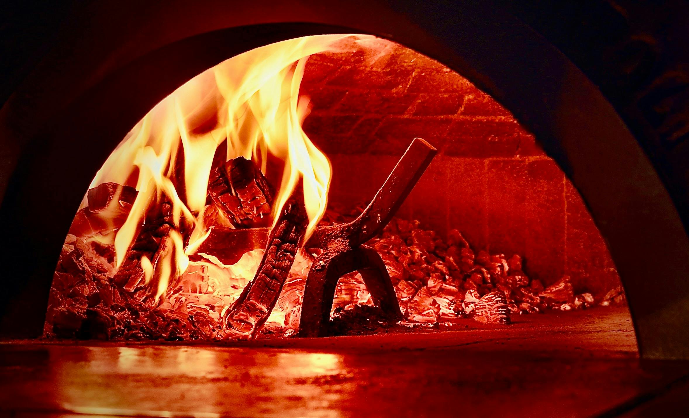 A photo of a wood-fired pizza oven w fire ablaze