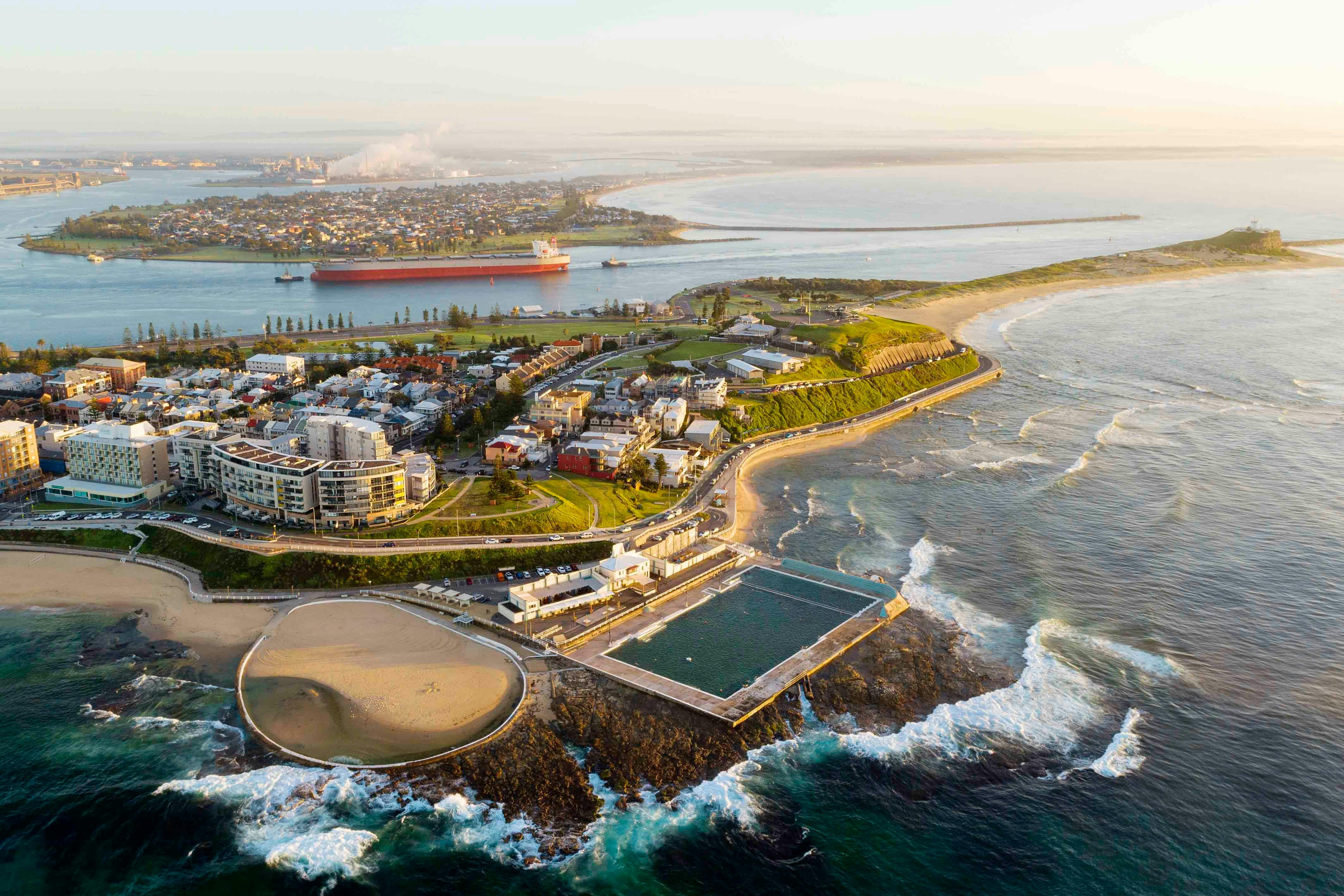 Aerial view of Newcastle Harbour and ocean baths at sunrise with soft morning light