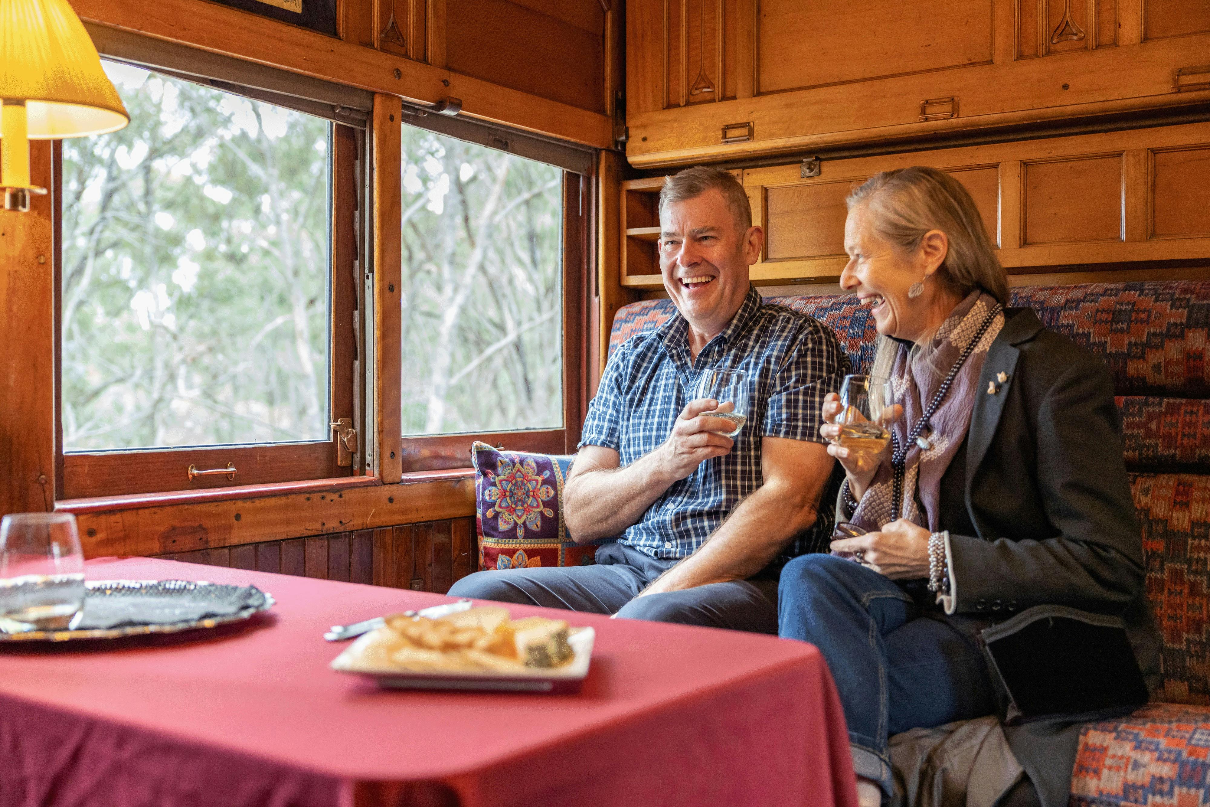 couple enjoying the sights and sounds of a steam train in a timber carriage, VGR Ales on Rails