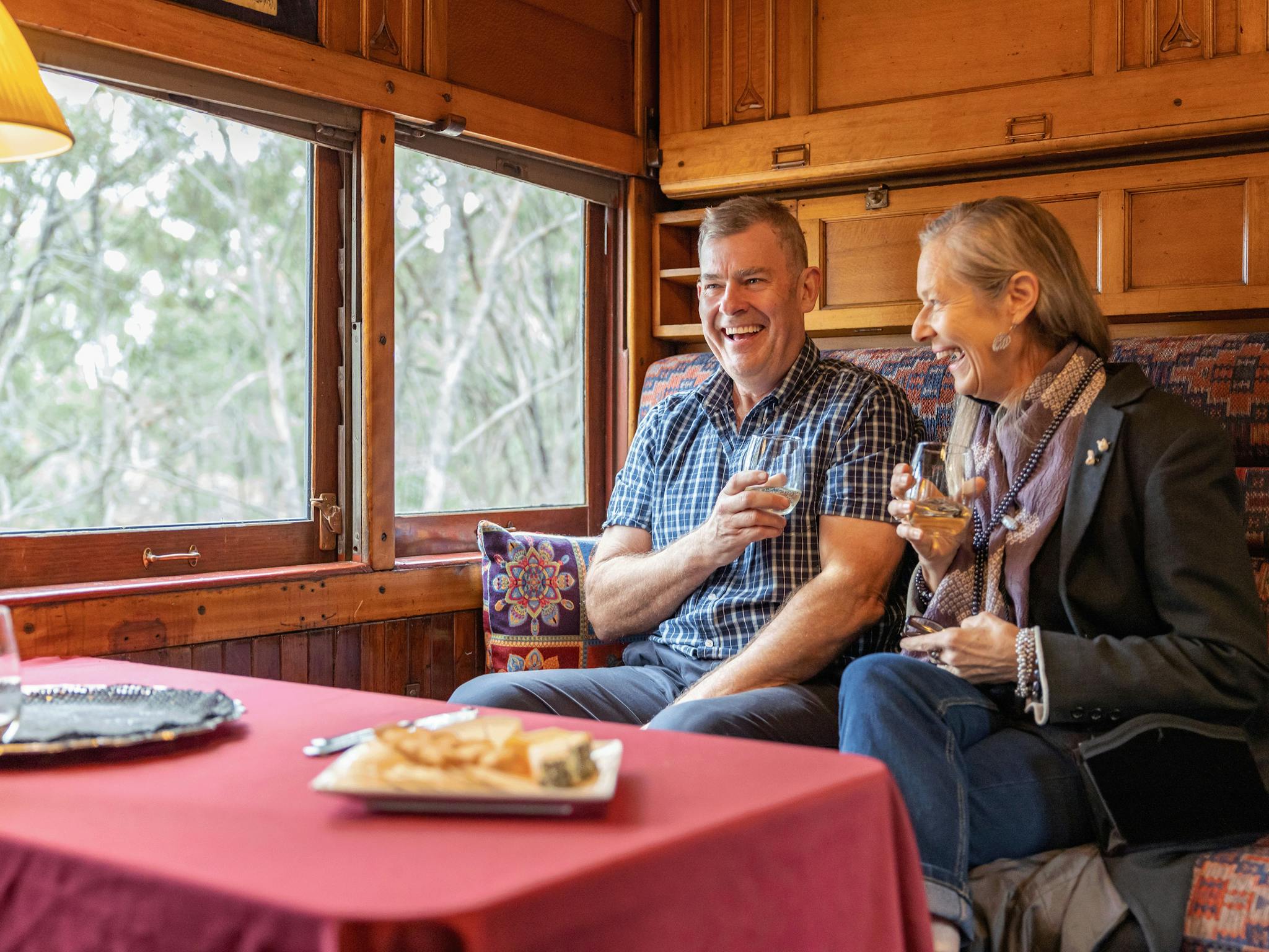 couple enjoying the sights and sounds of a steam train in a timber carriage, VGR Ales on Rails