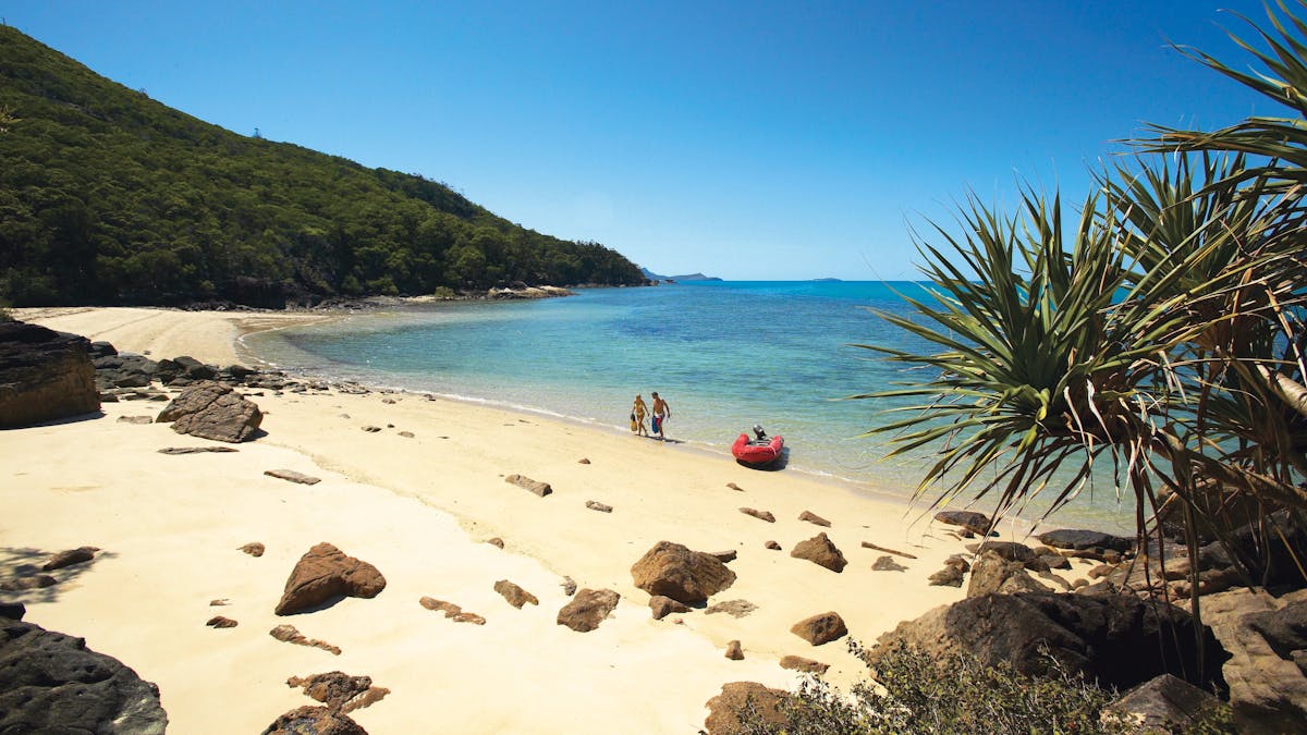 Small and private beach with a woman and a man walking out of the water with snorkelling gear