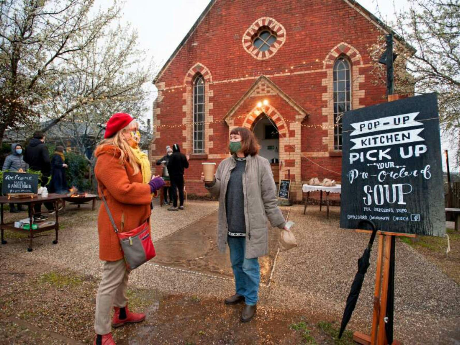 People gathering outside a red brick church.