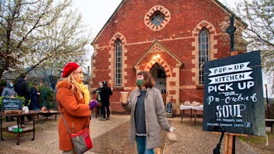 People gathering outside a red brick church.