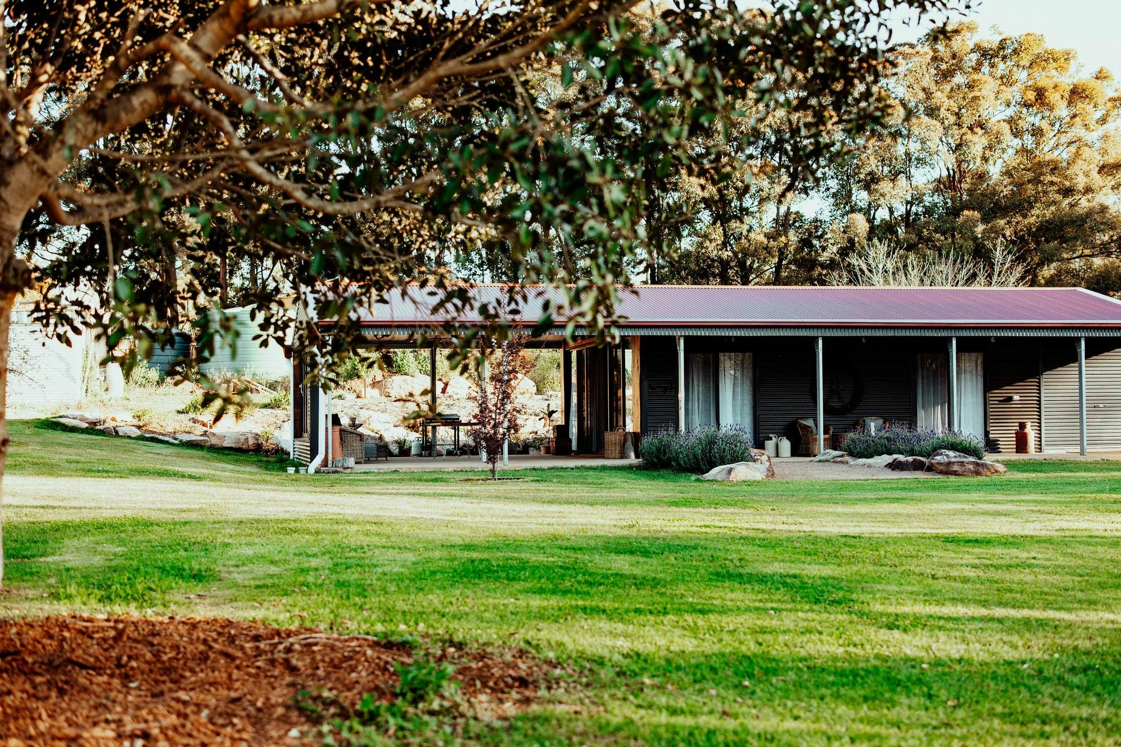 The Werombee Hive farm stay cottage surrounded by gardens and green lawns in Theresa Park, NSW