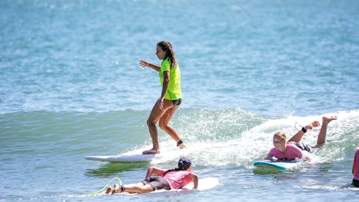 A surfer rides a wave in a group lesson