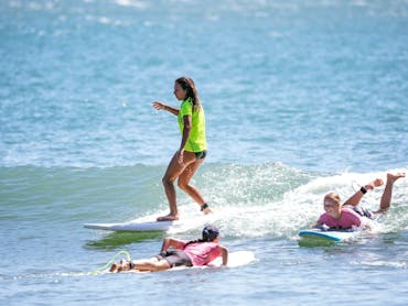 A surfer rides a wave in a group lesson