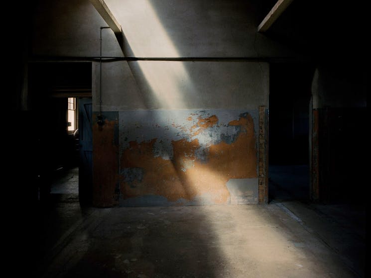 Moody old room with light beam shining through on grey and orange artwork