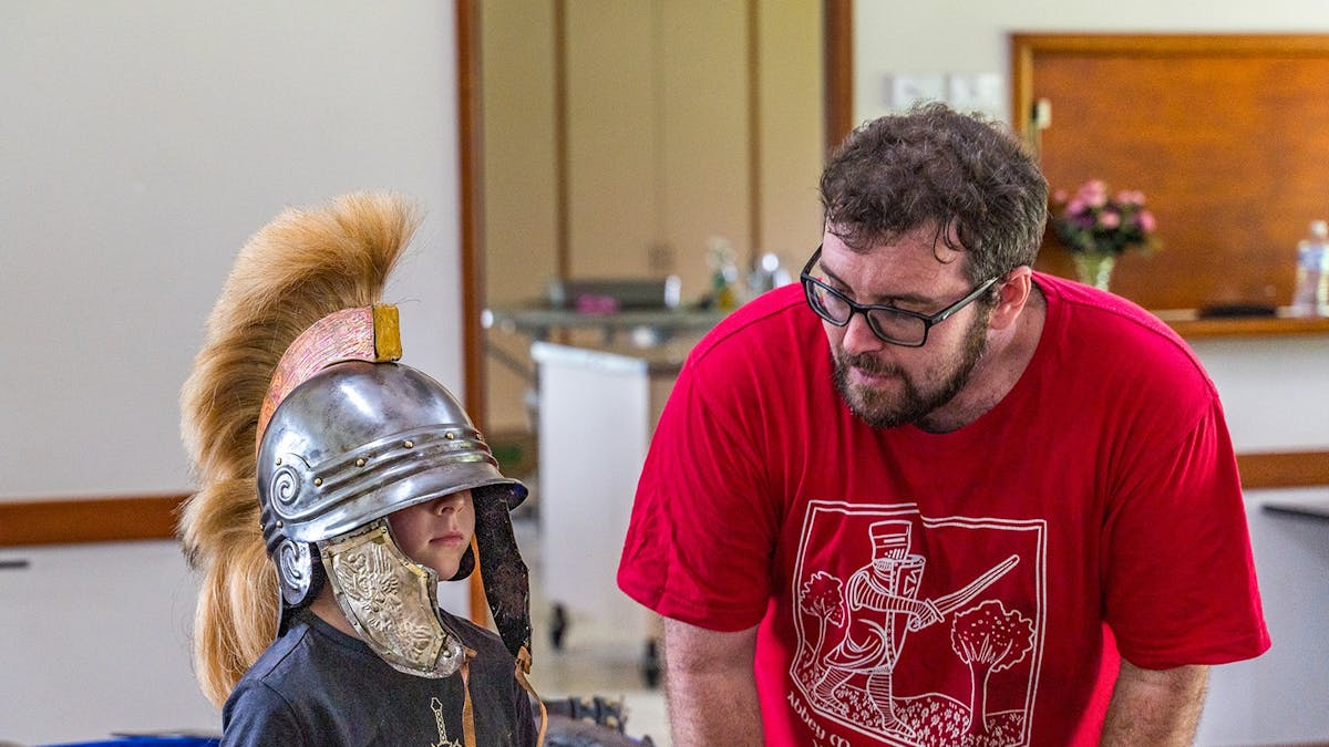 Child wearing Roman style helmet with Education Manager Benjamin