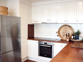Modern kitchen with timber benchtops, oven and electric cooktop.