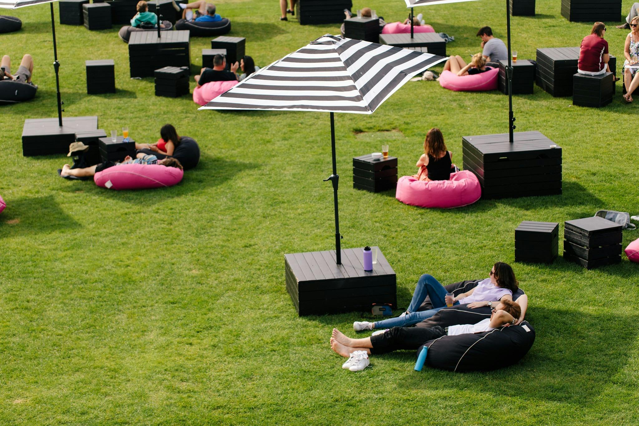 Mona lawns with people lounging in the sun on pink and black beanbags