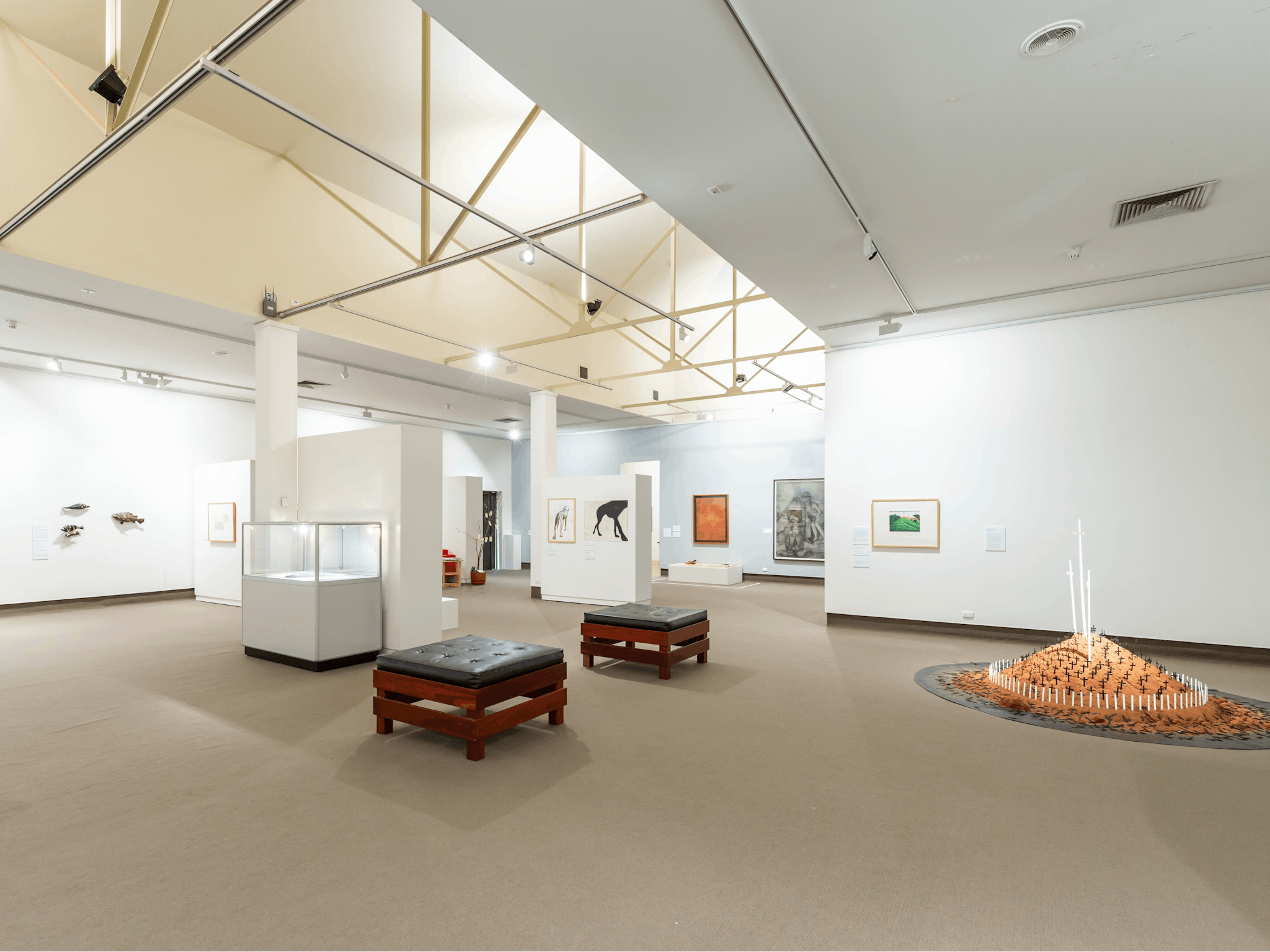 The image shows a light filled gallery with works from the permanent collection and local artists.