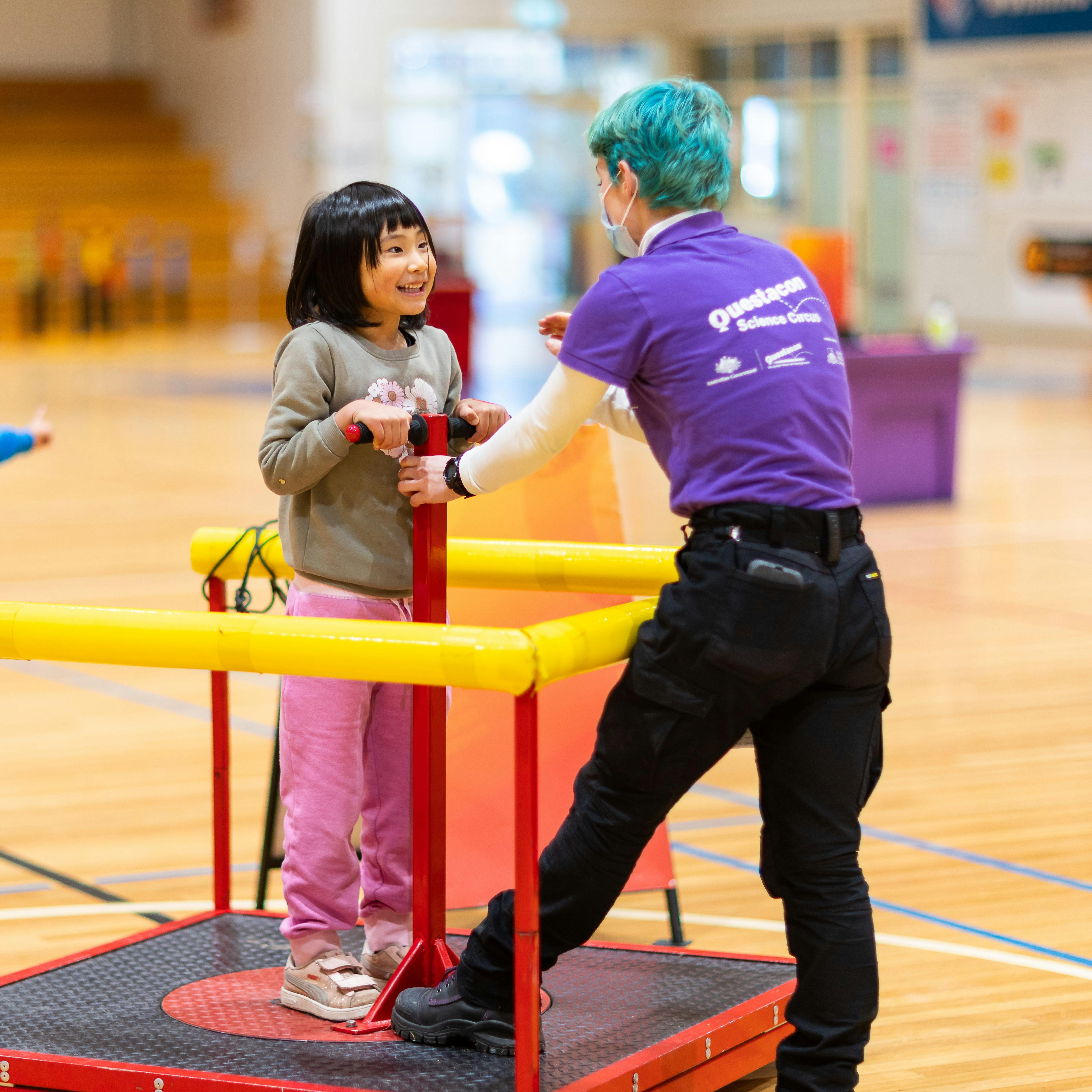 Questacon presenter spins a child on a rotating platform
