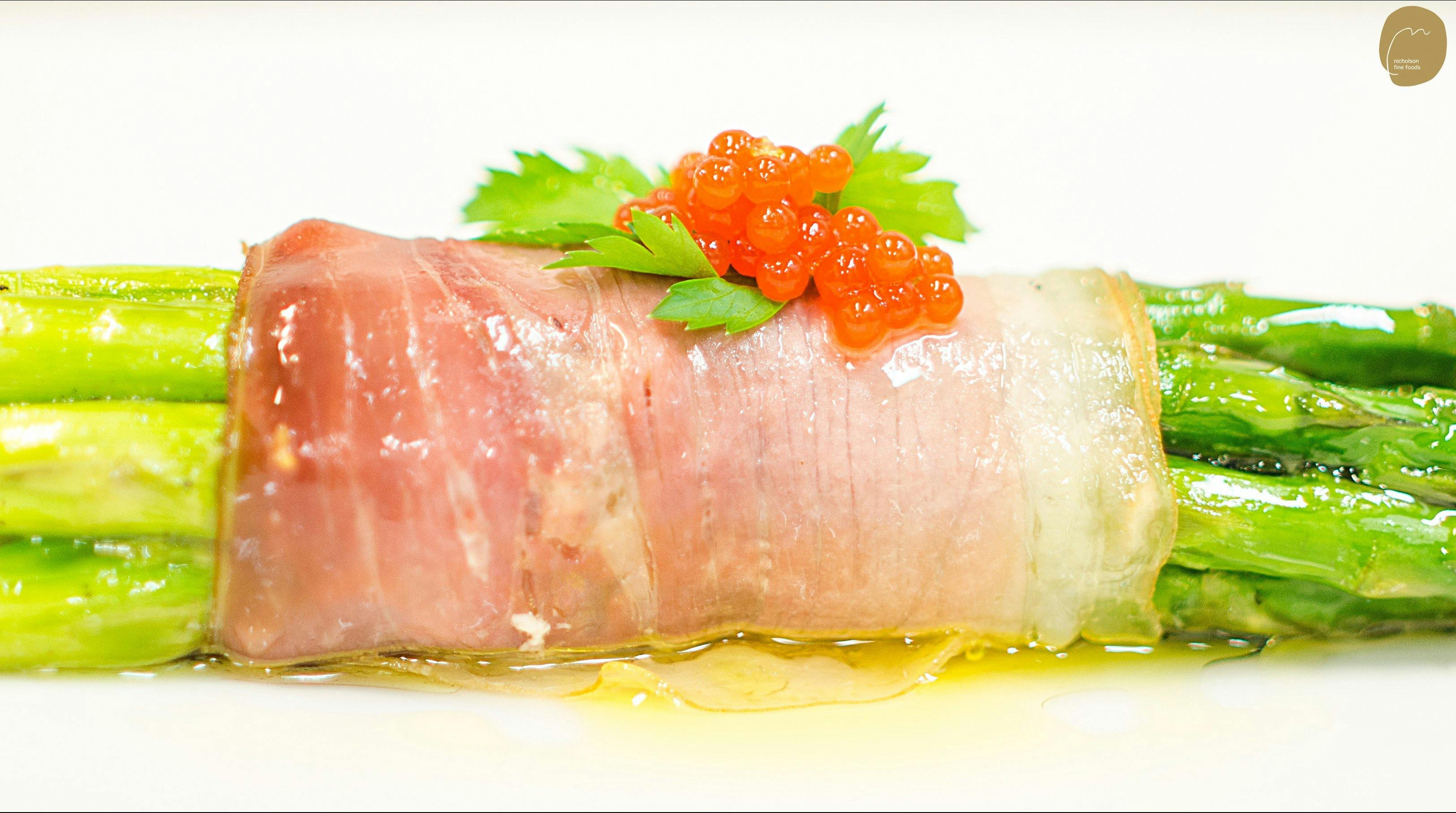 Red capsicum Garnishing Pearls on baked aparagus wrapped in proscuitto