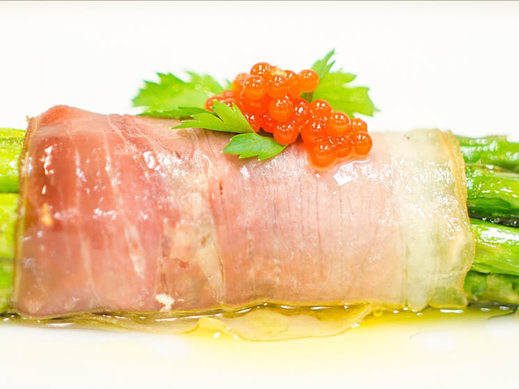 Red capsicum Garnishing Pearls on baked aparagus wrapped in proscuitto