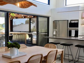 Open-plan dining and kitchen area flowing onto a covered outdoor entertaining deck at Harolds on the