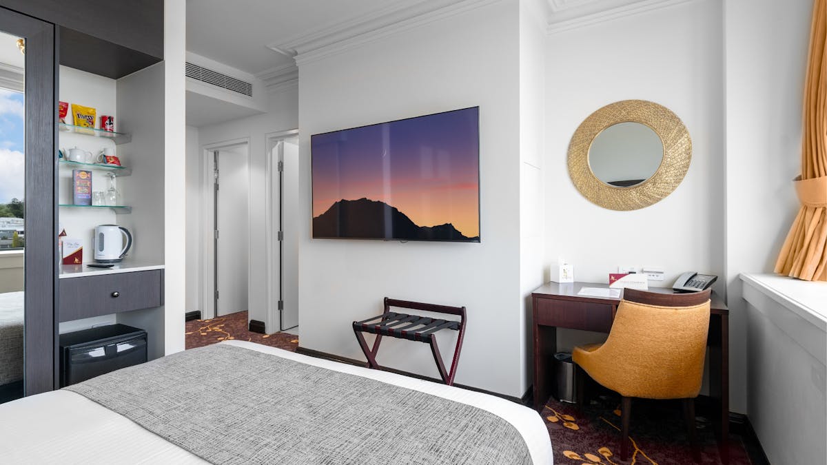 Layout of Corporate Queen Room featuring the desk, TV, mini fridge and minibar display