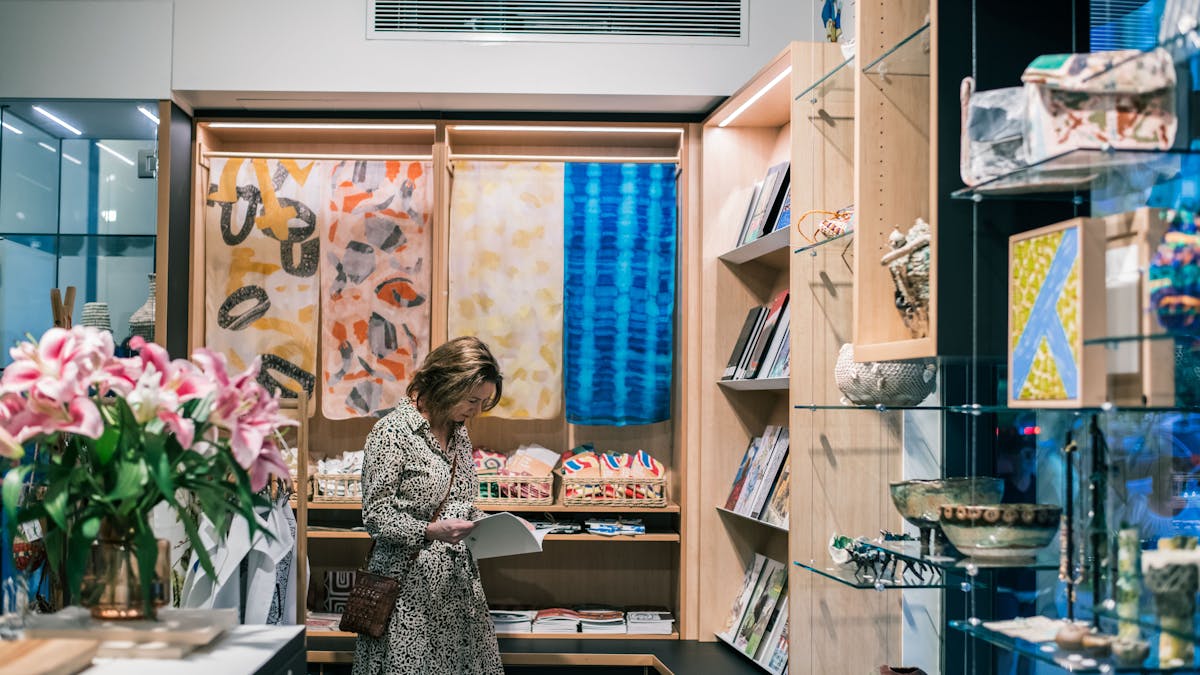 Woman reads an art catalogue surrounded by art, flowers and design objects in the NorthSite Store,