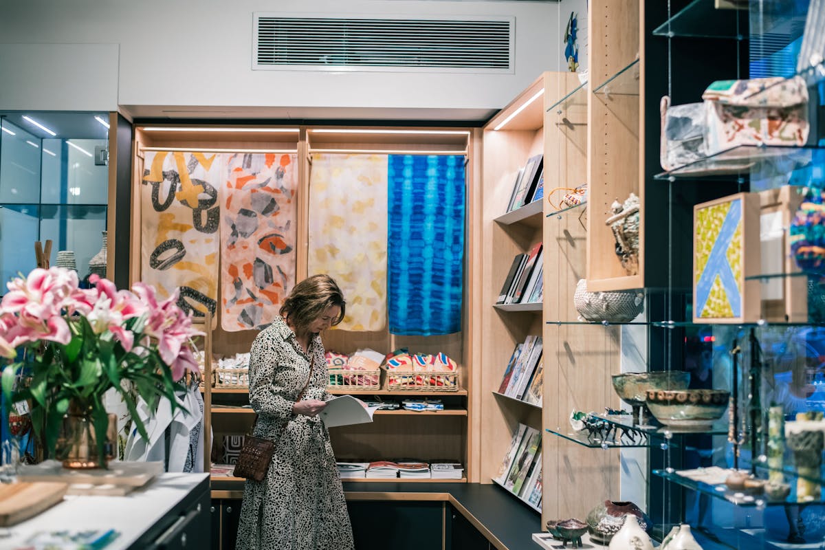 Woman reads an art catalogue surrounded by art, flowers and design objects in the NorthSite Store,