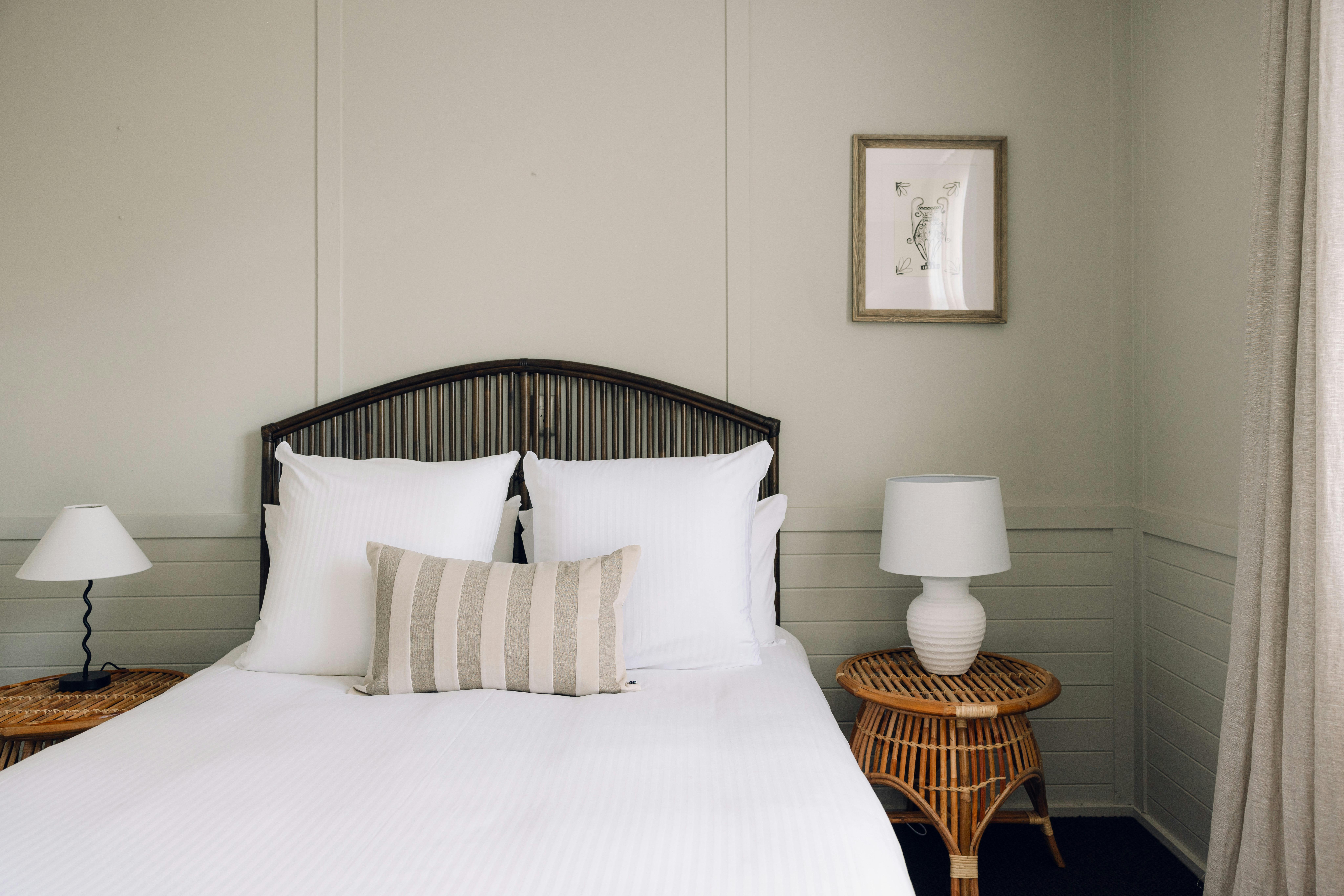 a queen bed and bedsides showing crisp white linen and a decorative striped cushion