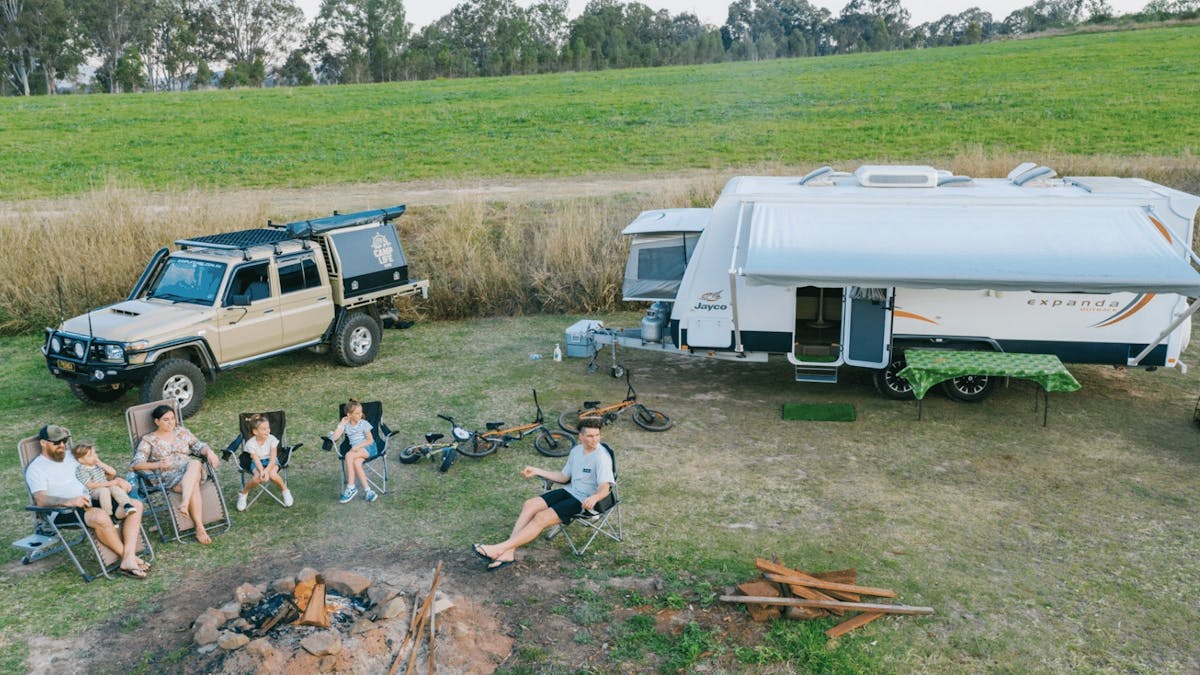 Family sitting around the fire with a caravan
