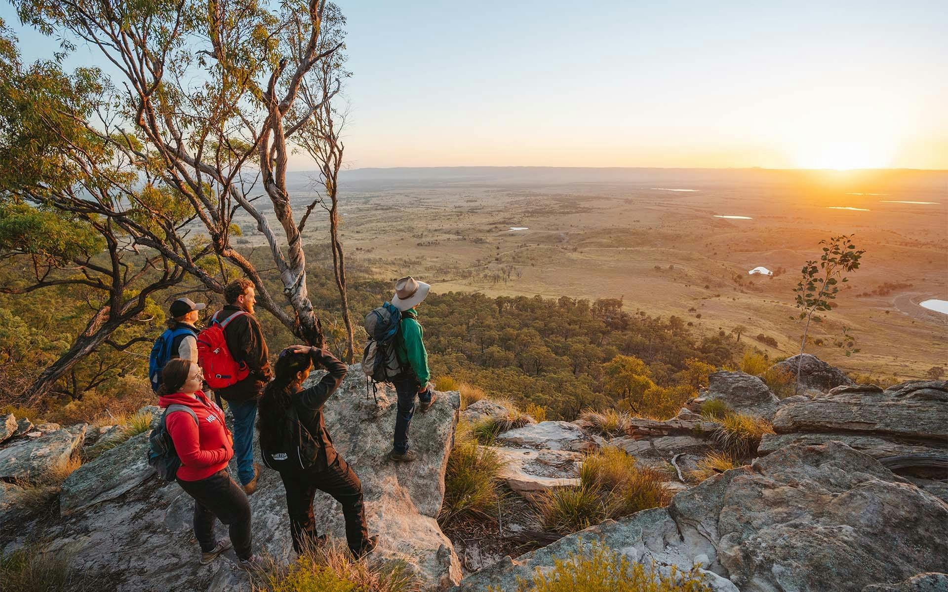 A tour group looking out at Arcadia Valley from a cliff edge at sunset