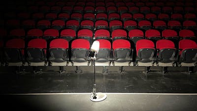 dimly lit image of light on a stand with red theatre seating in background