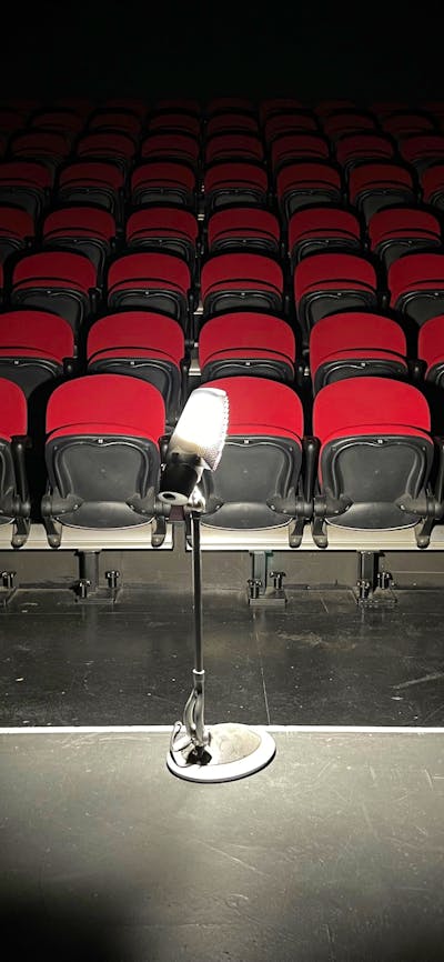 dimly lit image of light on a stand with red theatre seating in background