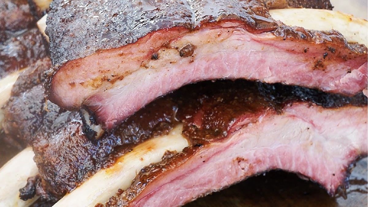 Close-up of Cape Grim smoked beef ribs with bark, smoke ring and juicy interior on a wooden board
