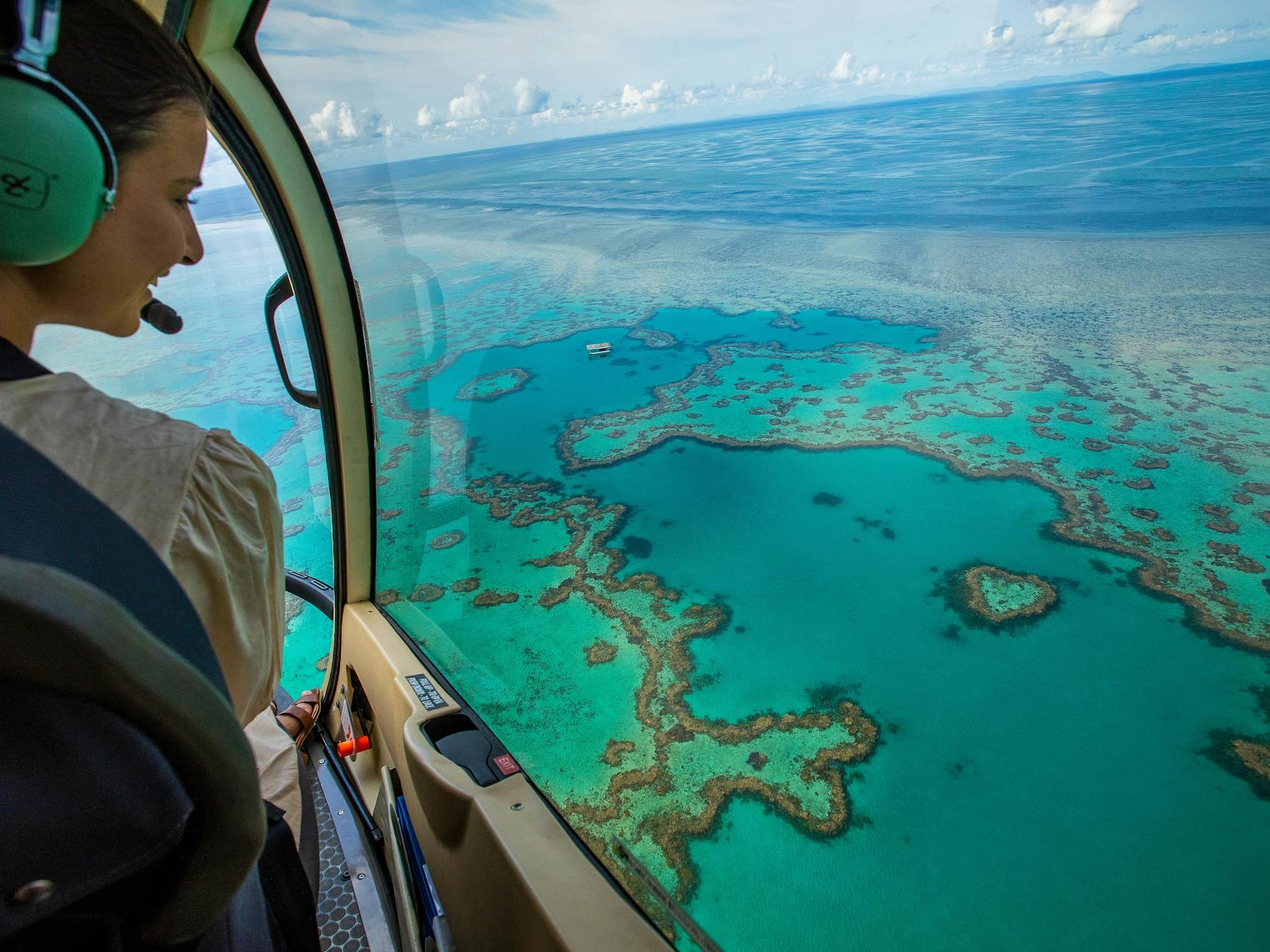 Aerial view from helicopter showing pilot looking down on heart reef and surrounding coral in sea