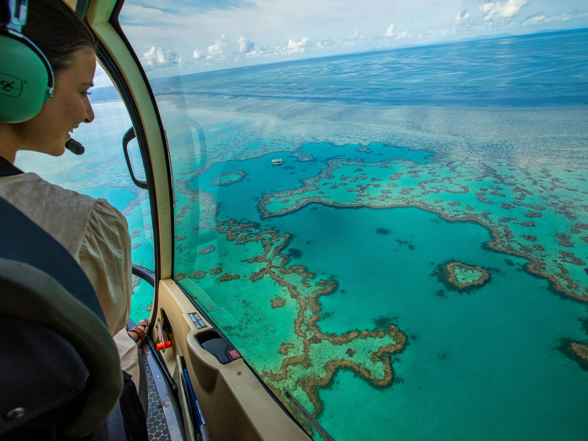 Aerial view from helicopter showing pilot looking down on heart reef and surrounding coral in sea