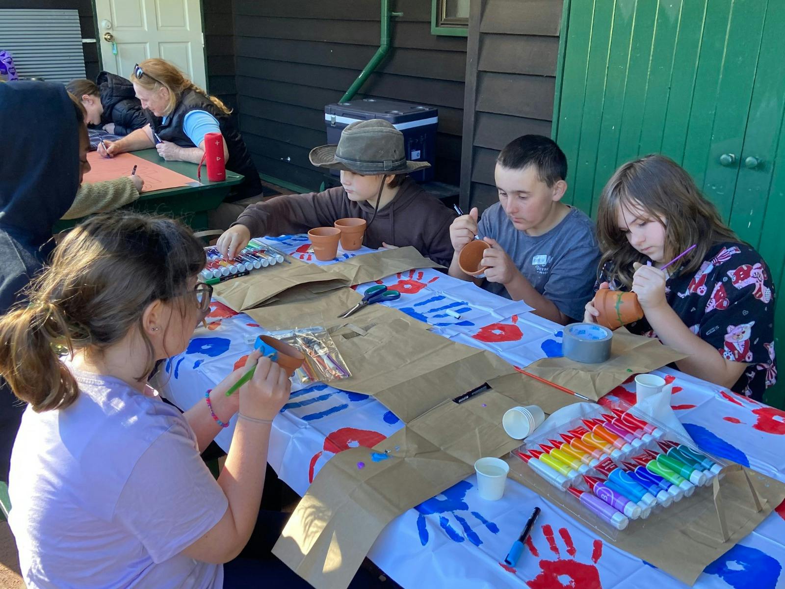 Kids gathered around a table enjoying a pot painting arts and craft activity