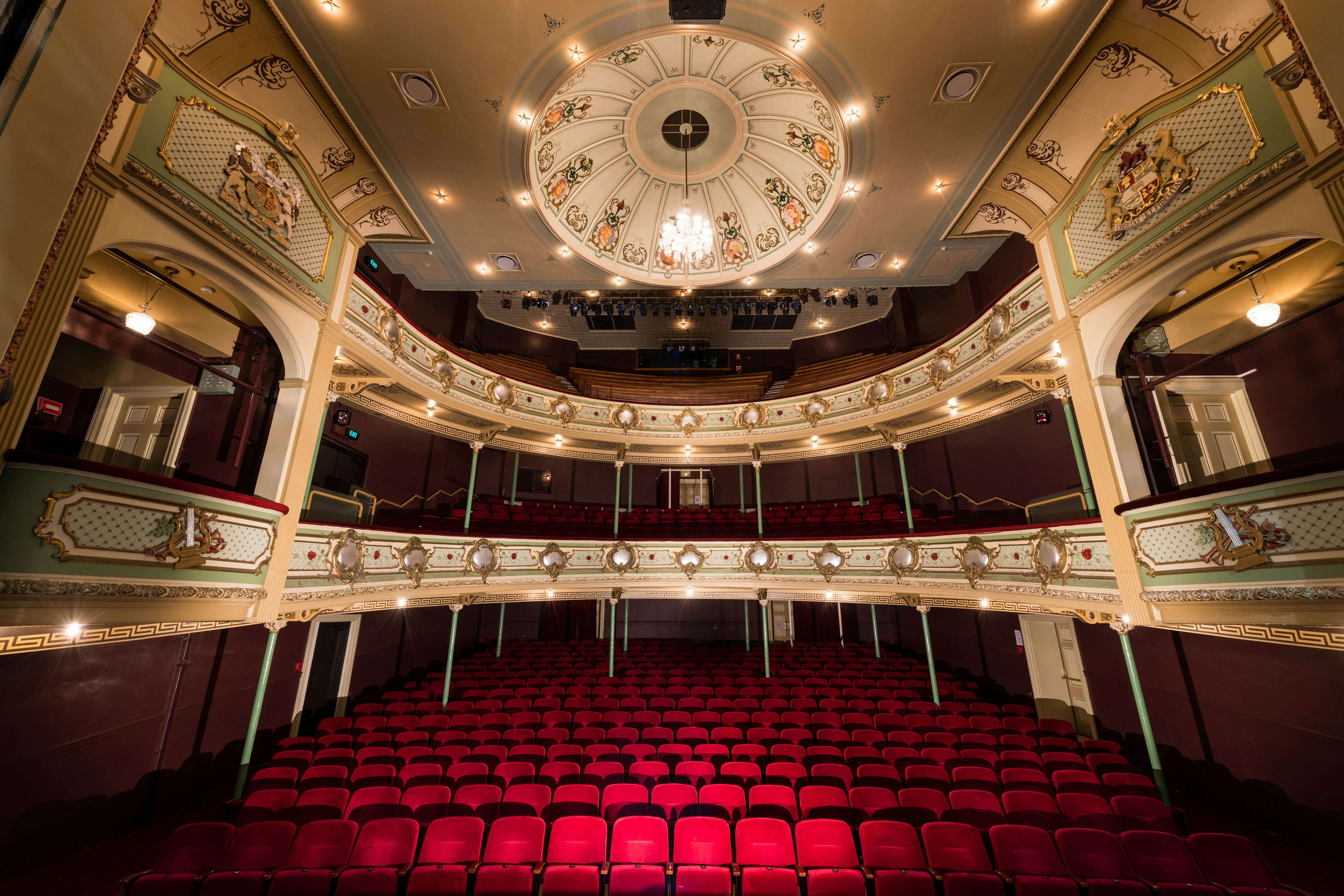 View of red velvet chairs and gold heritage balconies  from the stage of the Theatre Royal