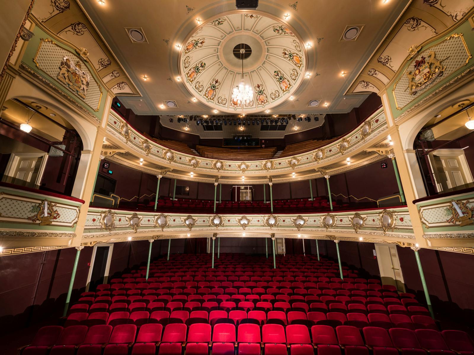 View of red velvet chairs and gold heritage balconies  from the stage of the Theatre Royal