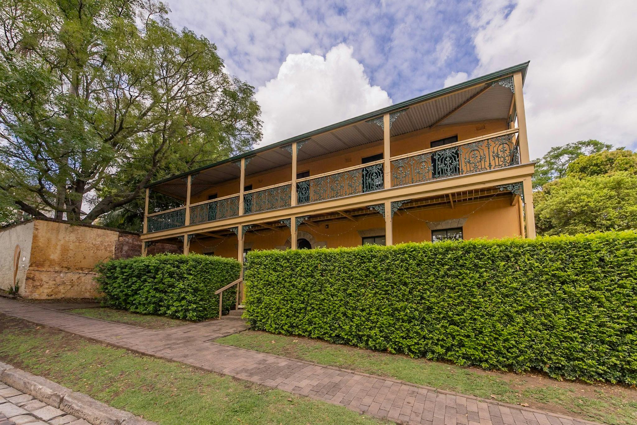 豪宅街景。歷史悠久的黃色建築，周圍環繞著綠色樹籬。