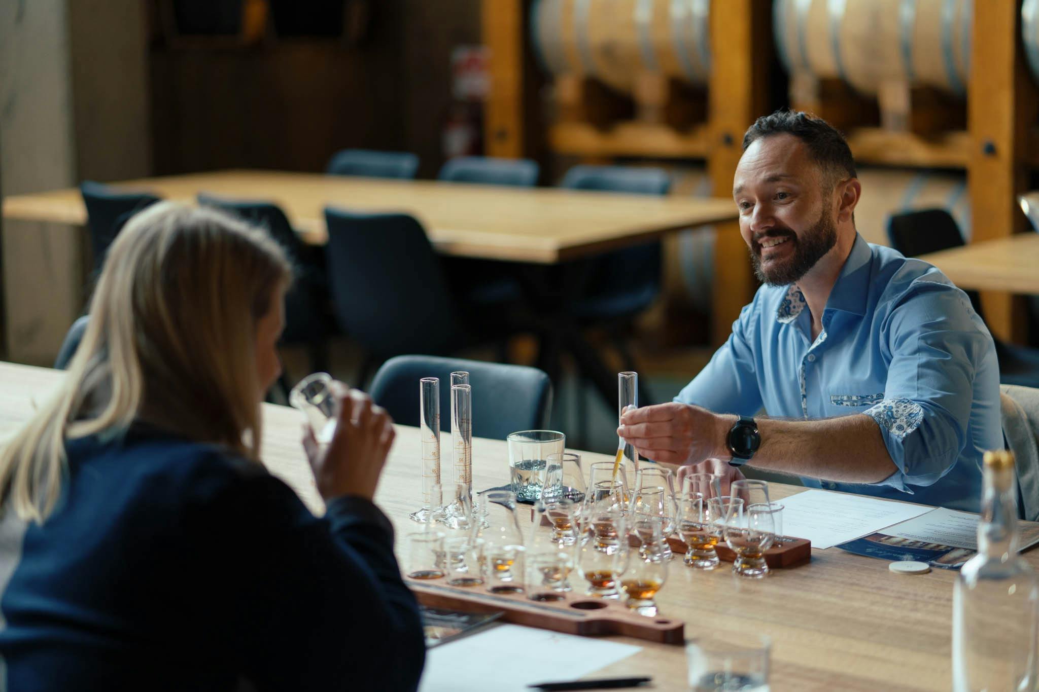 Man and woman sitting at table sampling whiskies