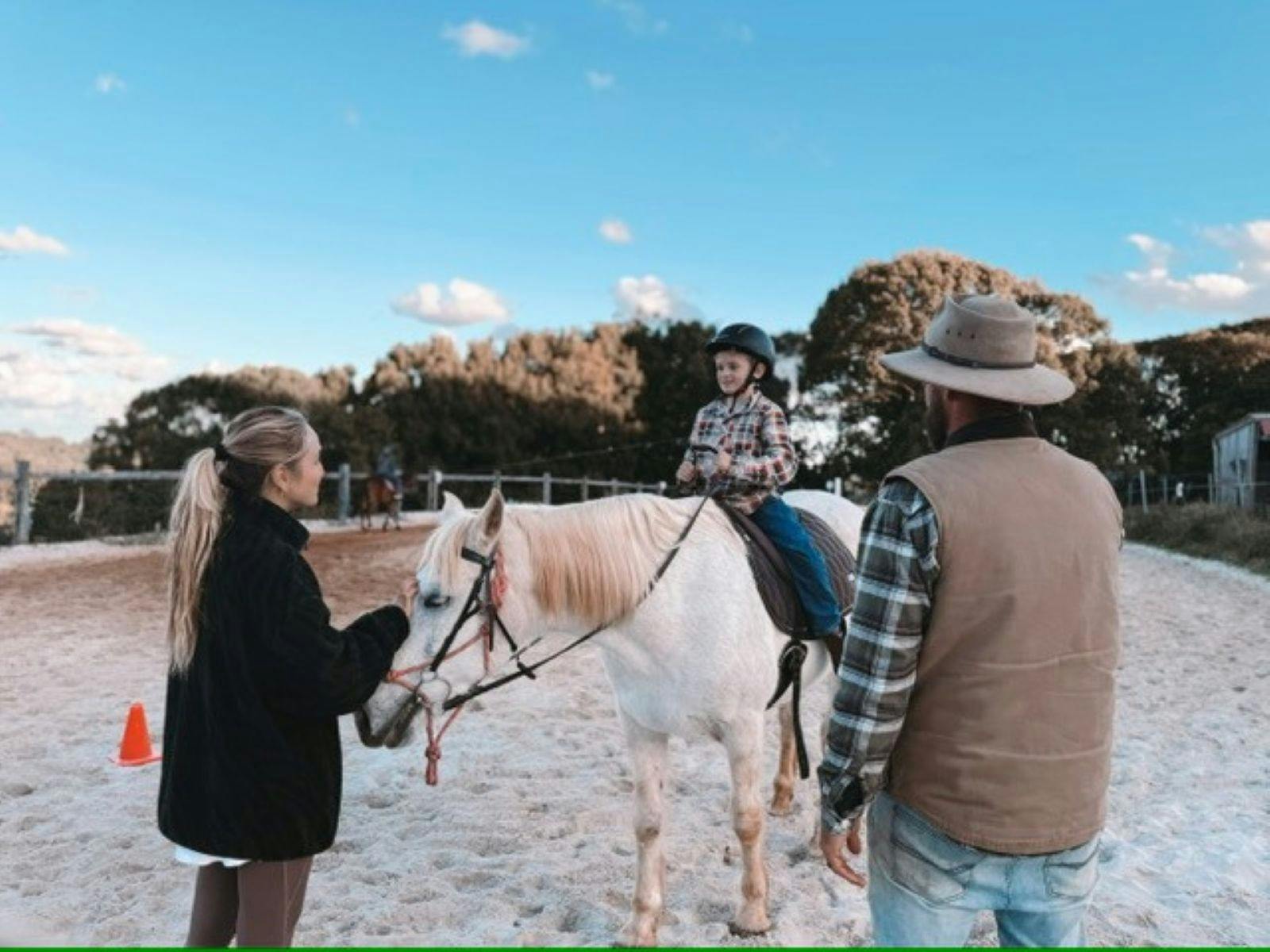 Boy sitting on horse with trainer
