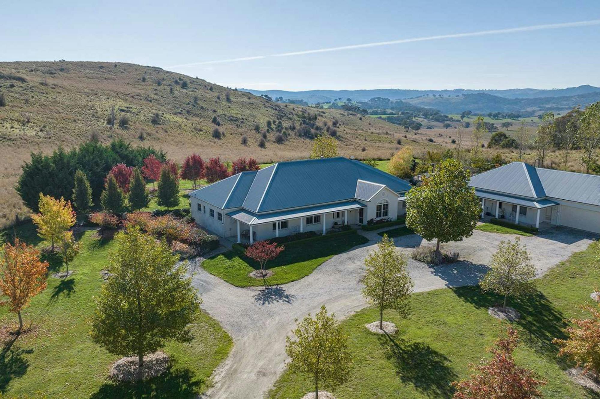 Rolling hills with photo of house, grey roof and large garden