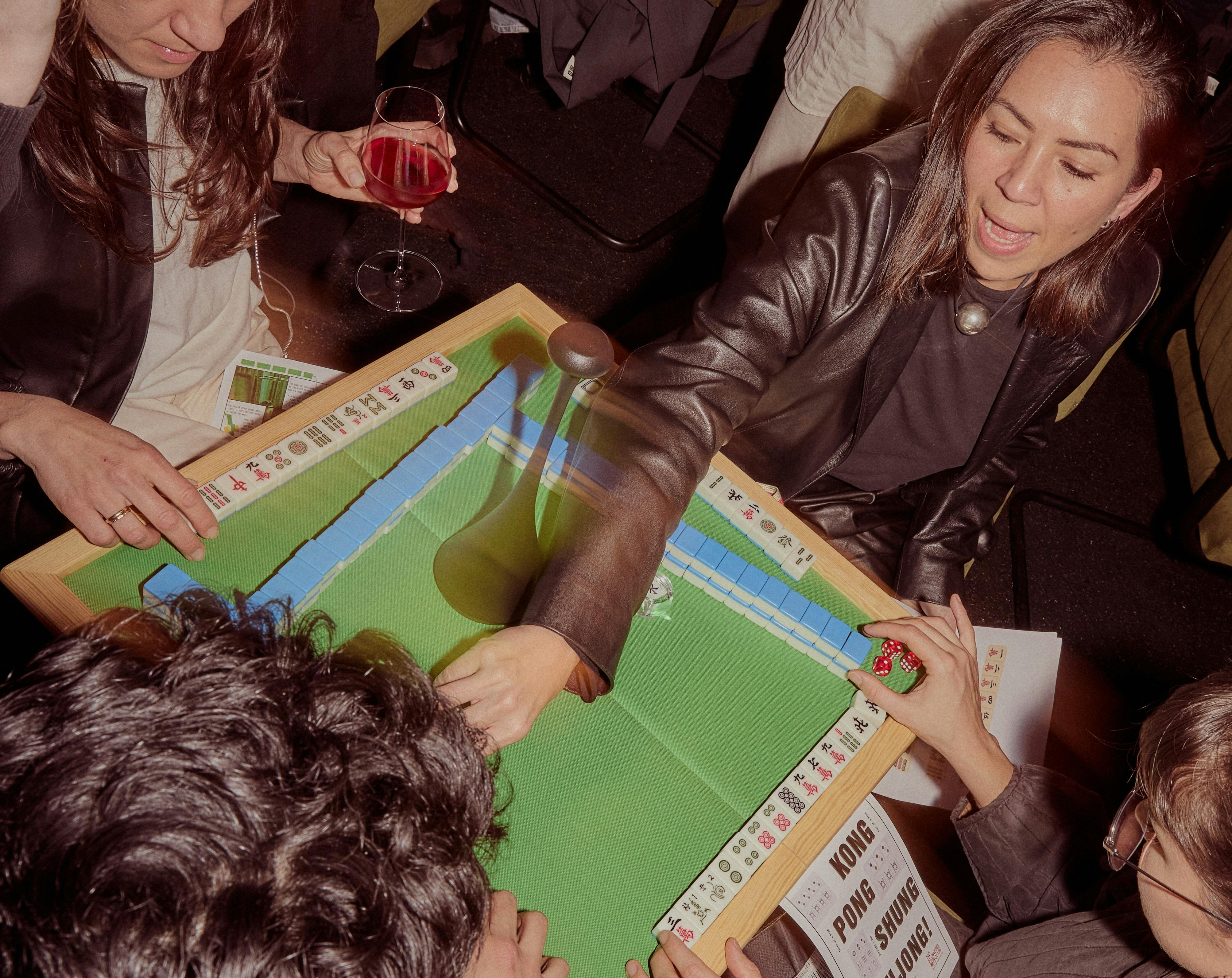 A photograph of people laughing and playing mahjong.