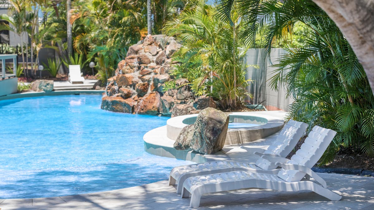 Pool with white lounge chairs nearby