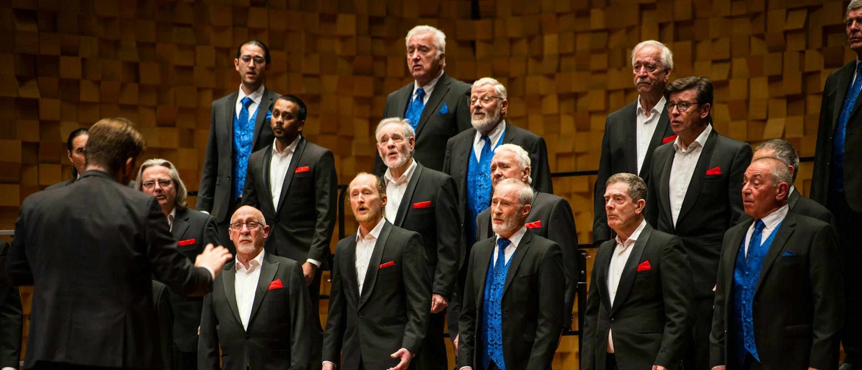 A group of men wearing grey suits and blue waistcoats singing