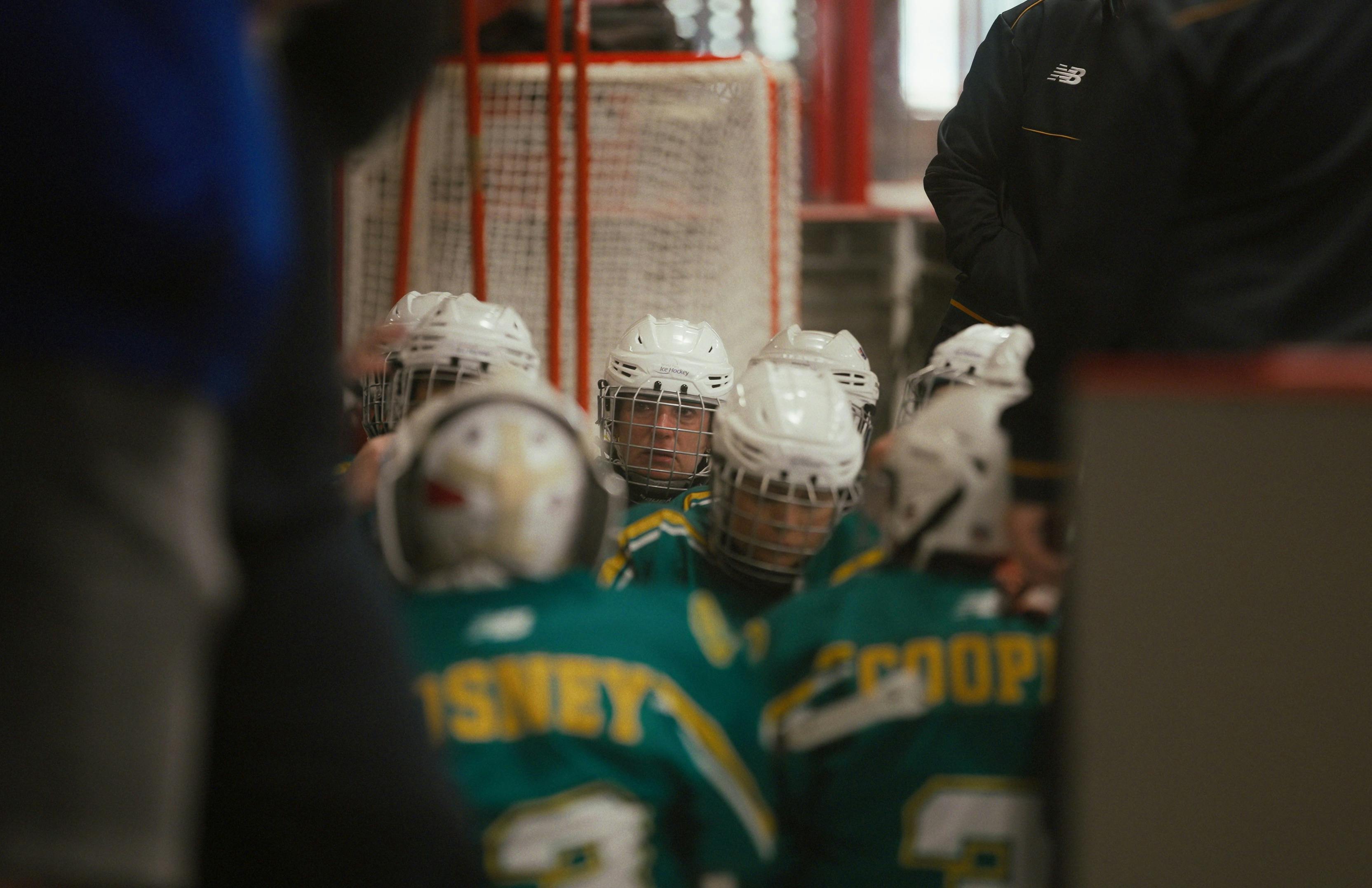 one player looks through a sea of green and gold helmets towards the coach giving instructions