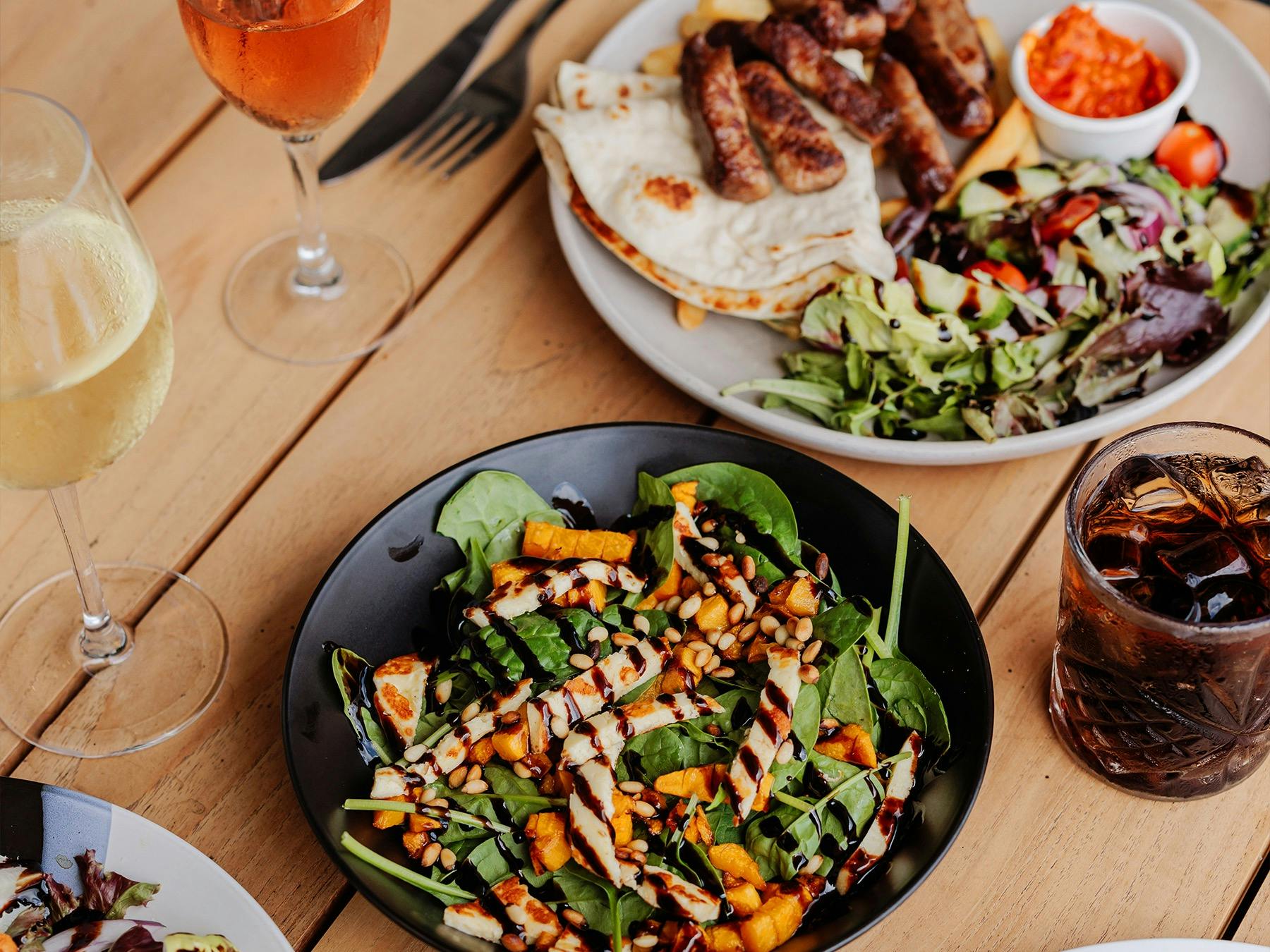 Colourful cepavi plate with pumpkin salad and refreshing drinks served on a rustic table