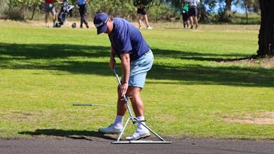 Male golfer scraping sand greens