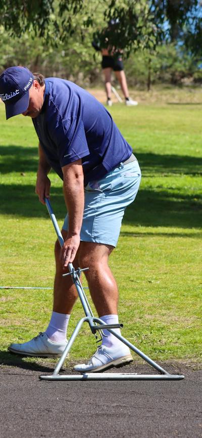 Male golfer scraping sand greens