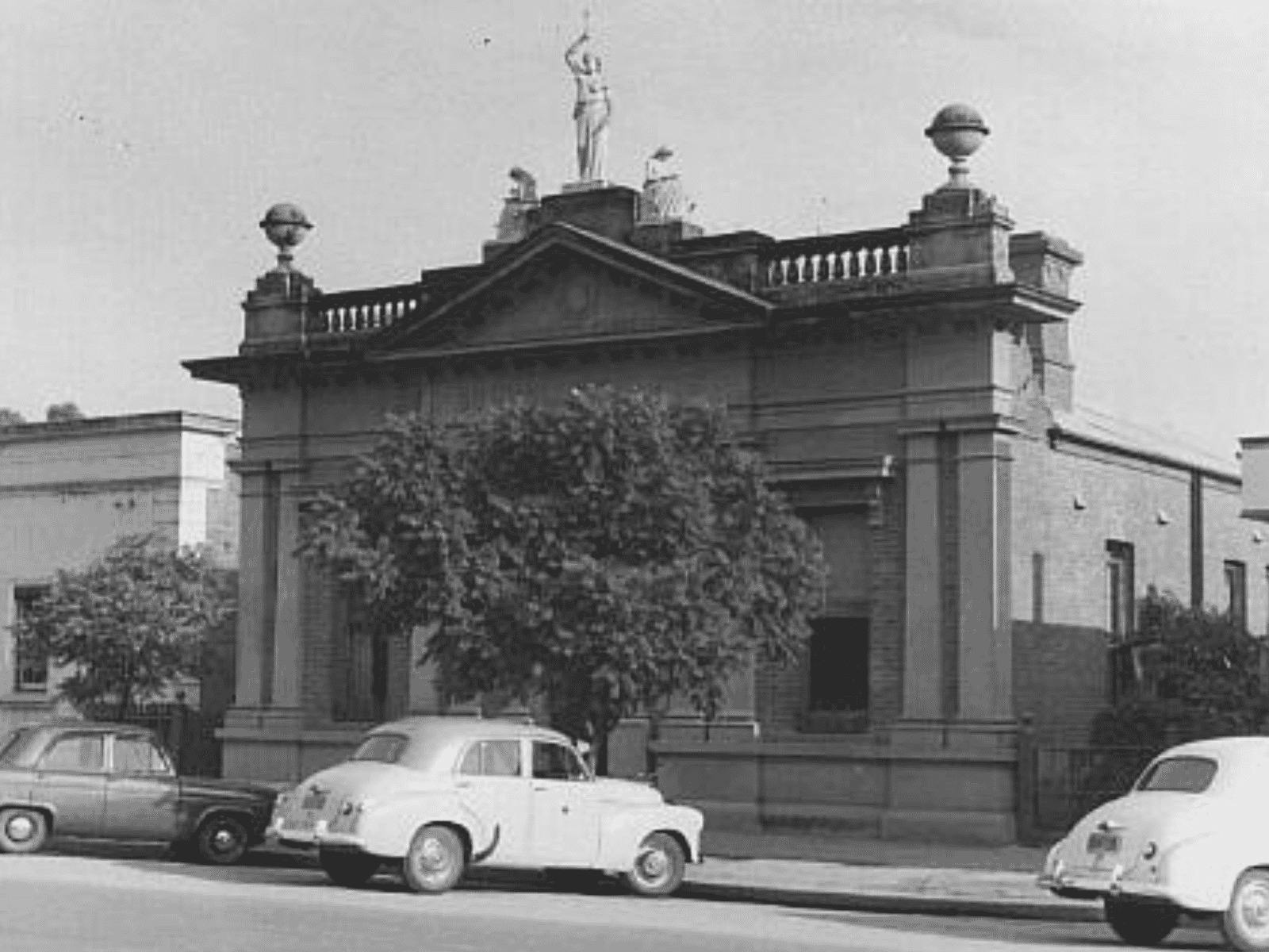 A black and white photo of a European style building with the muse statues on top.
