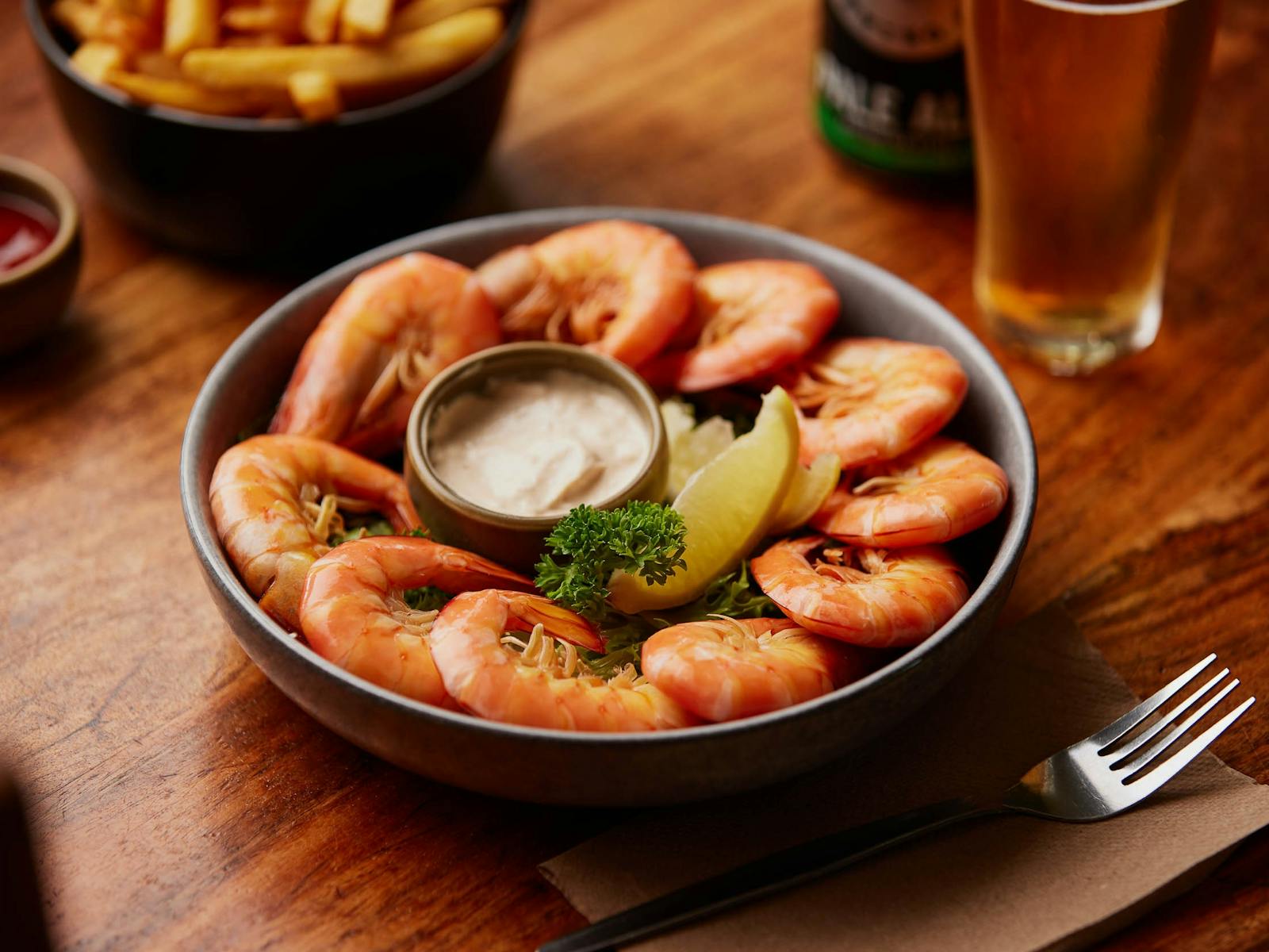 A bowl of cooked prawns and cocktail dipping sauce
